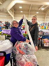 Two Moms Holding a very long reciept in front of a shopping bag that was just purchased.